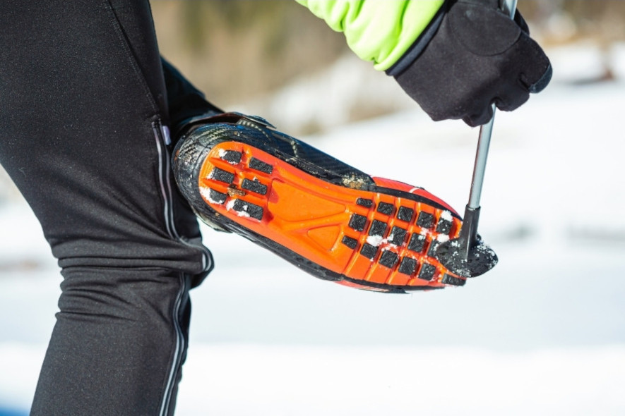 Skrapar bort snö under längdskidpjäxorna